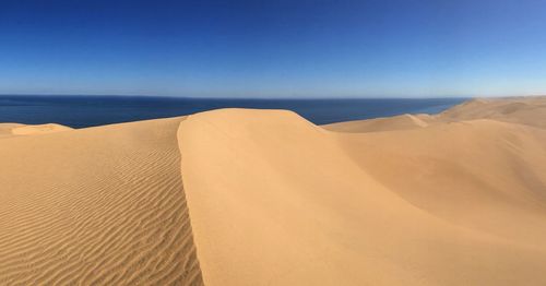 Scenic view of sand dunes against sea
