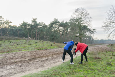 Rear view of man and woman on field against sky