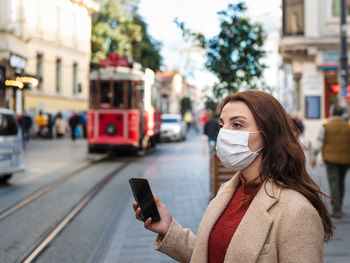 Young woman using mobile phone in city