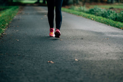 Low section of woman walking on road