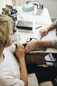 Hands of male nurse checking student's blood pressure in school office