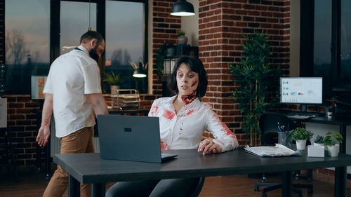 Spooky woman using laptop at office