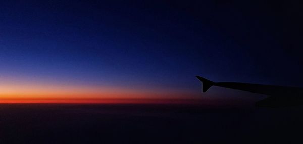 Airplane wing against clear sky during sunset