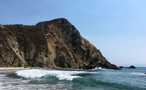 Rock formation in sea against clear sky