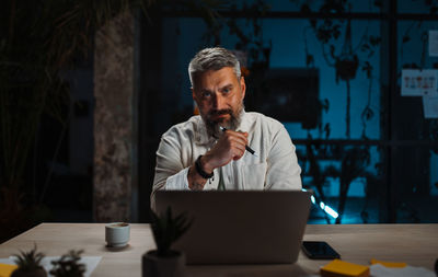 Relaxed man posing to the camera while working at contemporary evening office