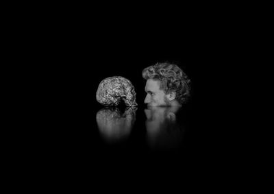 Digital composite image of man with skull against black background
