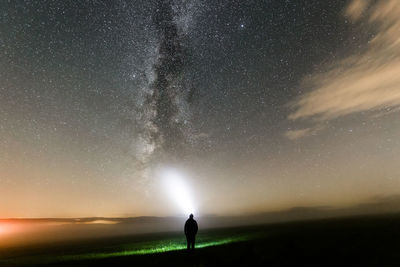 Rear view of man standing against sky at night