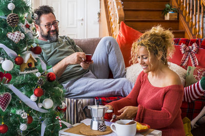 People sitting by christmas tree