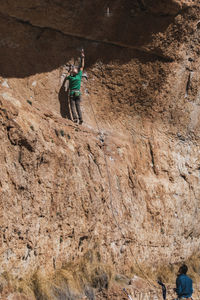 Climber attaching safety rope to a rock helped by a colleague