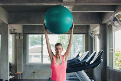 Young woman holding fitness ball in gym