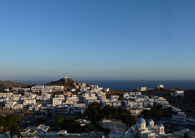 Aerial view of townscape by sea against clear blue sky