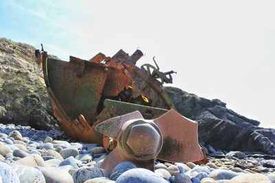 Old rusty wheel on beach against clear sky