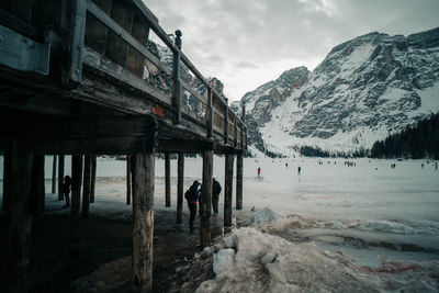 People on snowcapped mountain against sky during winter