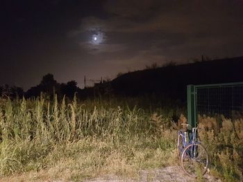 Bicycle on field against sky at night