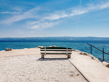 Minimalist image of empty sea bench on sea shore on a sunny day in summer.