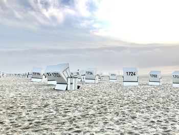 Hooded chairs on beach against sky