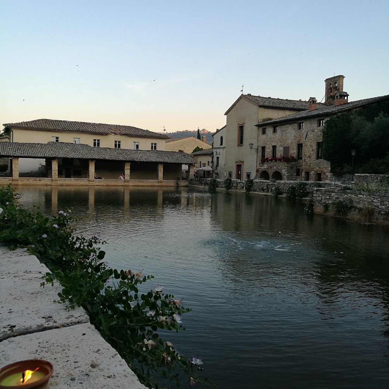 BUILDINGS BY RIVER AGAINST CLEAR SKY