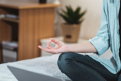 Midsection of woman meditating at home
