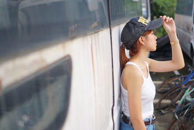 Side view of woman with arms raised standing outdoors