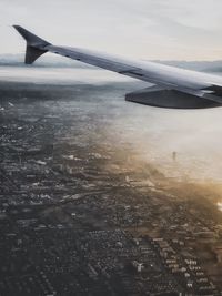 Airplane flying over cityscape against sky