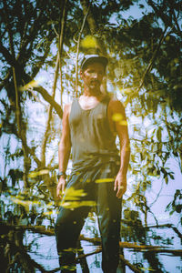 Digital composite image of young man standing by tree in forest