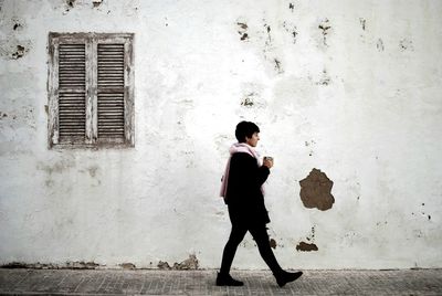 Woman walking on footpath against old building