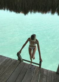 High angle view of young woman moving up on ladder in sea