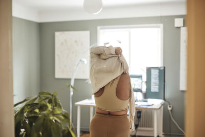 Rear view of woman with disability wearing dress while standing at home