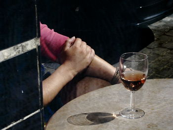 Cropped hands of man by wineglass on table in restaurant