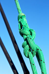 Low angle view of rope tied up against blue sky