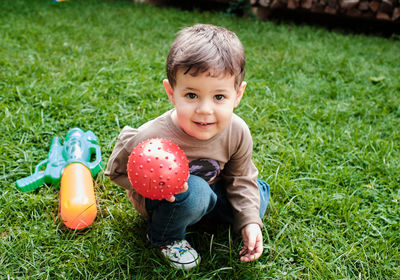 Beautiful toddler is playing with a ball in the backyard