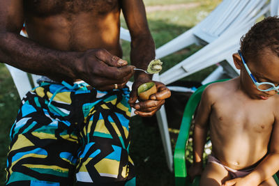 Midsection of father feeding kiwi to son