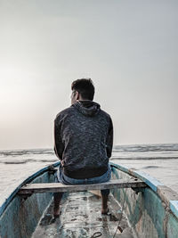 Rear view of man looking at sea against clear sky