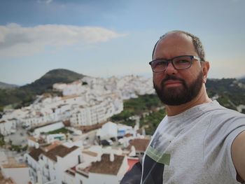 Mature man wearing eyeglasses against cityscape