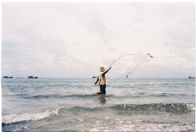 Man fishing in sea against sky