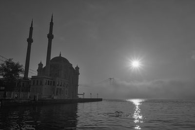 View of building by water against sky and fog