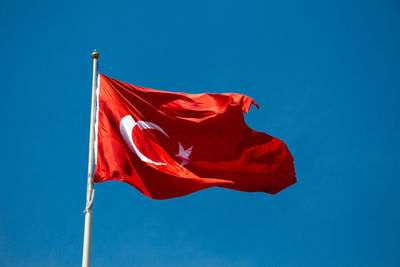 Low angle view of flag against blue sky