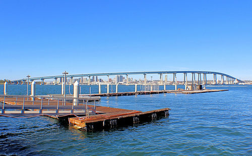 Bridge over sea against clear blue sky