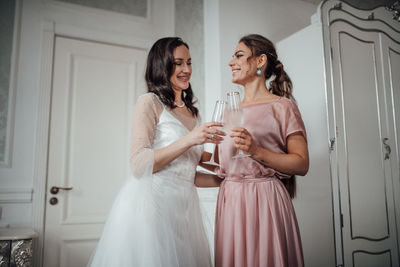 Bridesmaid and bride holding champagne flute