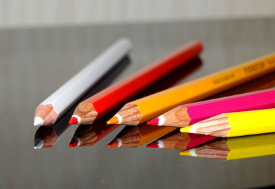 Close-up of colorful pencils on glass table with reflection