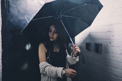 Young woman with umbrella standing in rain