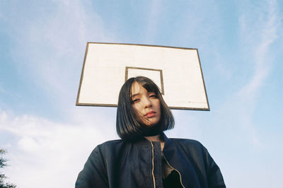 Low angle view of young woman against sky