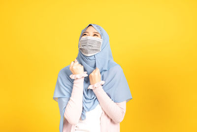 Portrait of a person standing against yellow background