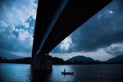 Bridge over river against cloudy sky