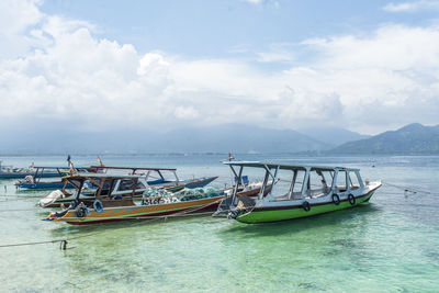 Fishing boats moored in sea against sky