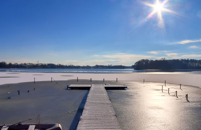 Snow covered wooden jetty at a frozen lake on a sunny day in germany