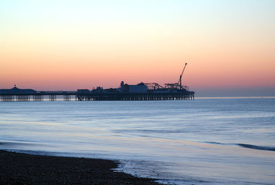 Silhouette pier over sea against sky during sunset