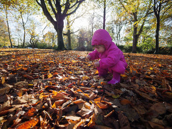 Girl crouching on field during autumn