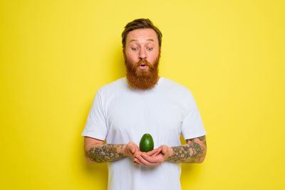 Mid adult man holding ice cream against yellow background