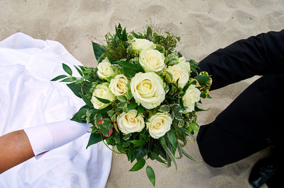 High angle view of bride and groom holding bouquet at beach